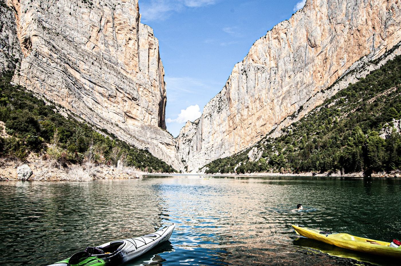 Kayaks on a river between canyon walls